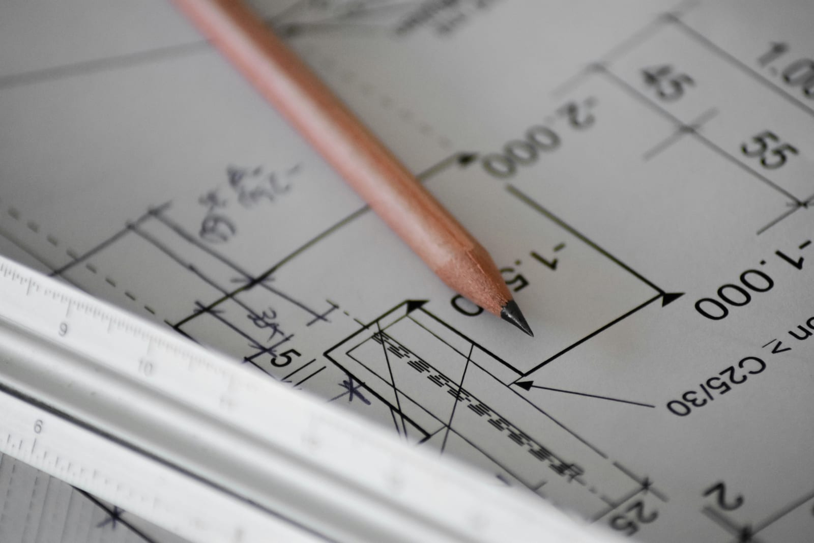 A pencil and a scale rule resting on a marked up technical drawing.